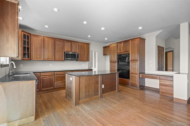 kitchen featuring black appliances, a sink, light wood-style flooring, recessed lighting, and brown cabinets