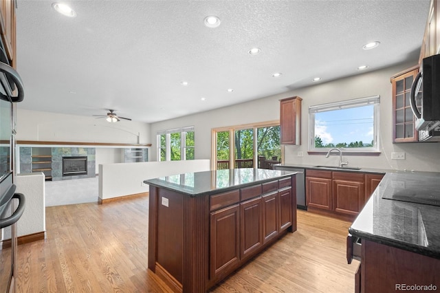 kitchen with a sink, stainless steel dishwasher, a ceiling fan, light wood-style floors, and a center island
