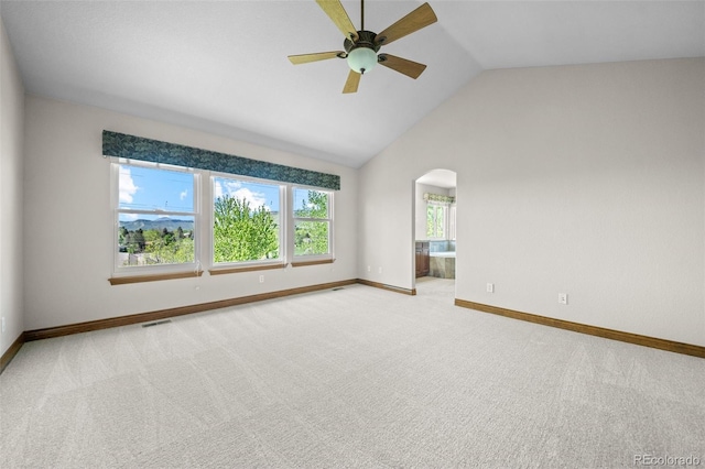 carpeted empty room featuring ceiling fan, baseboards, arched walkways, and high vaulted ceiling