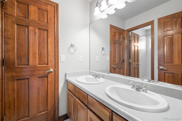 bathroom featuring double vanity, a textured wall, a chandelier, and a shower