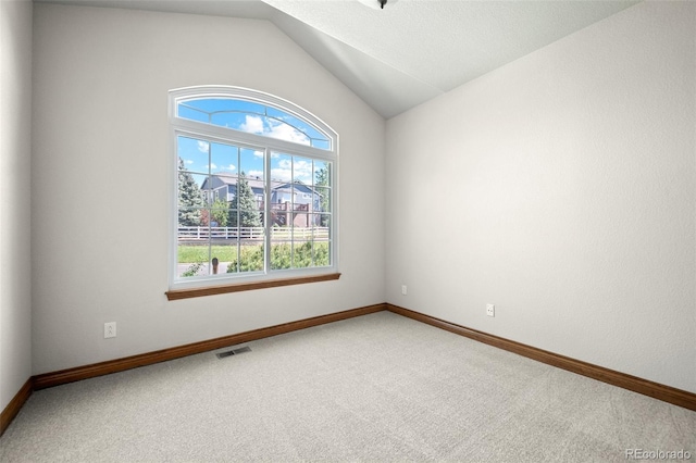 unfurnished room with carpet floors, healthy amount of natural light, lofted ceiling, and baseboards