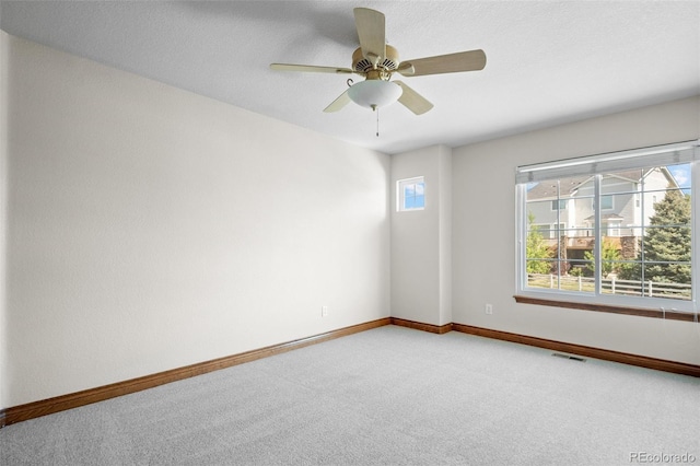 carpeted empty room featuring baseboards and a ceiling fan