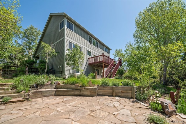 back of property with stairs, a wooden deck, and a patio