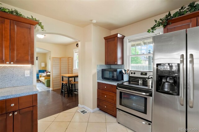 4779 S Bannock St, Englewood, CO 80110 - kitchen with stainless steel appliances, arched walkways, tasteful backsplash, and plenty of natural light