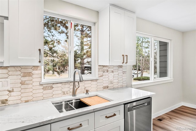 kitchen featuring white cabinetry, sink, light stone counters, and stainless steel dishwasher