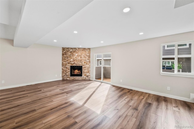 unfurnished living room with a stone fireplace and light hardwood / wood-style floors