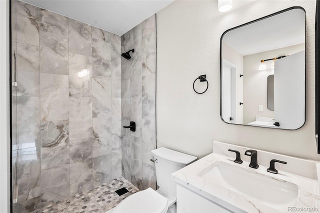 bathroom featuring vanity, tiled shower, and toilet