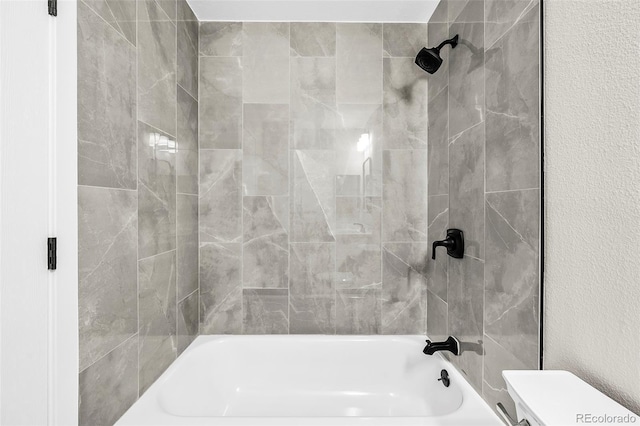 bathroom with tiled shower / bath combo and toilet