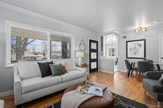 living area with baseboards, wood finished floors, and a chandelier
