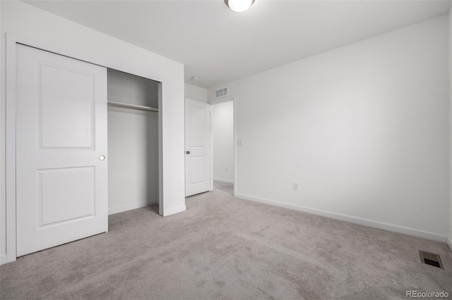 unfurnished bedroom with light colored carpet and a closet