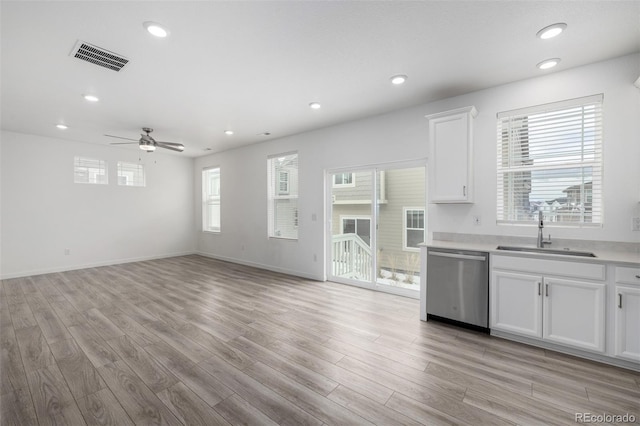 kitchen with a healthy amount of sunlight, dishwasher, sink, and white cabinets