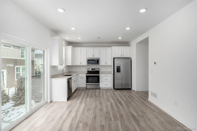 kitchen with white cabinetry, sink, stainless steel appliances, and a healthy amount of sunlight