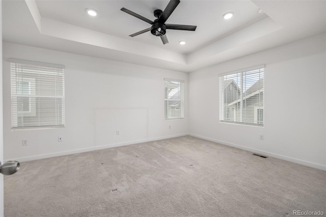 carpeted empty room featuring ceiling fan and a tray ceiling