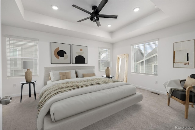 carpeted bedroom with ceiling fan and a tray ceiling