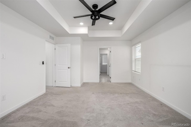 unfurnished bedroom featuring light carpet, a raised ceiling, and ceiling fan