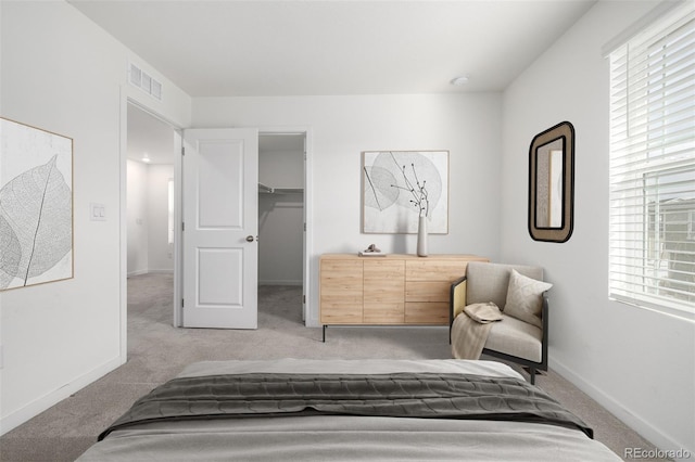 carpeted bedroom with a walk in closet and a closet