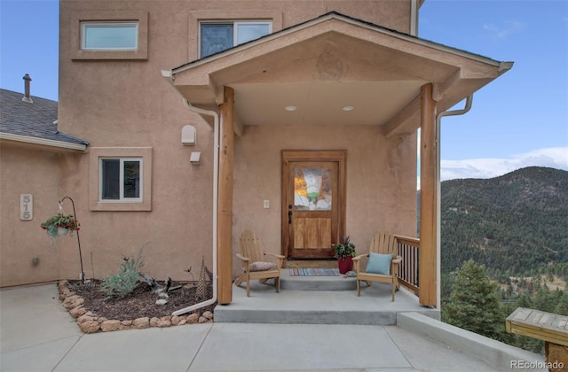 view of exterior entry featuring stucco siding and a mountain view