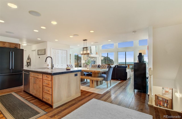 kitchen featuring high quality fridge, stainless steel dishwasher, dark wood finished floors, a sink, and open floor plan