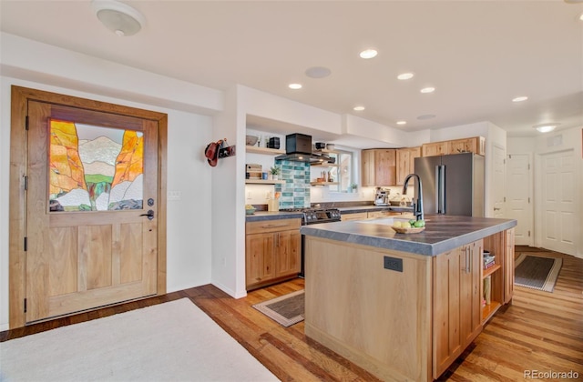 kitchen featuring wall chimney range hood, dark countertops, open shelves, and appliances with stainless steel finishes