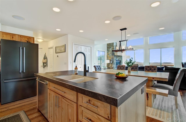 kitchen featuring high quality fridge, dark countertops, open floor plan, and a sink
