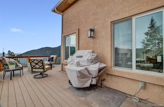 wooden terrace with an outdoor hangout area, a mountain view, and grilling area