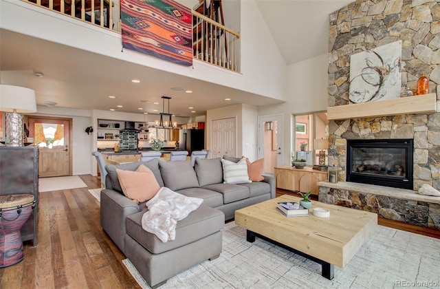 living area featuring a fireplace, vaulted ceiling, wood-type flooring, and a notable chandelier