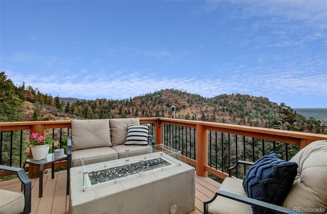 wooden deck with an outdoor living space with a fire pit and a mountain view