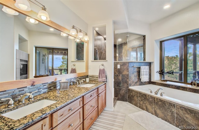 bathroom with a garden tub, tiled shower, and a sink