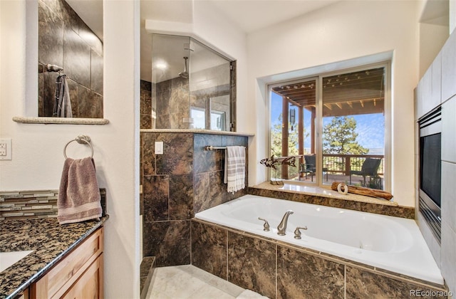 full bath featuring tiled shower, a garden tub, and vanity