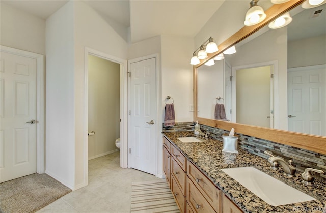 full bath featuring toilet, tasteful backsplash, and a sink