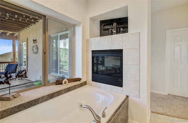 bathroom featuring a tile fireplace, a garden tub, and tile patterned flooring
