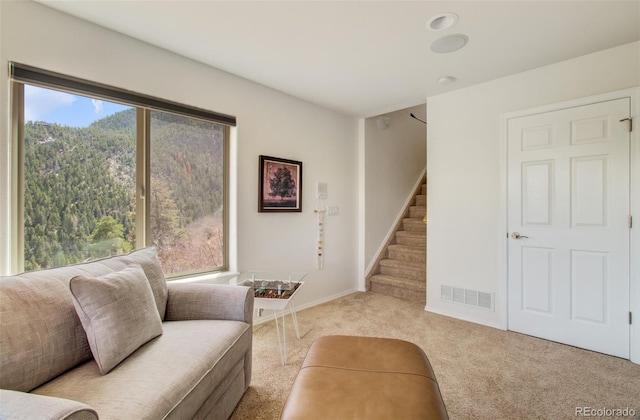 carpeted living room featuring baseboards, stairs, and visible vents