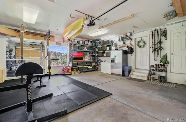 garage featuring a garage door opener and stainless steel refrigerator with ice dispenser