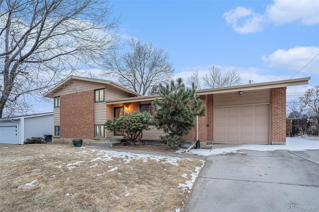 split level home with a garage, concrete driveway, and brick siding