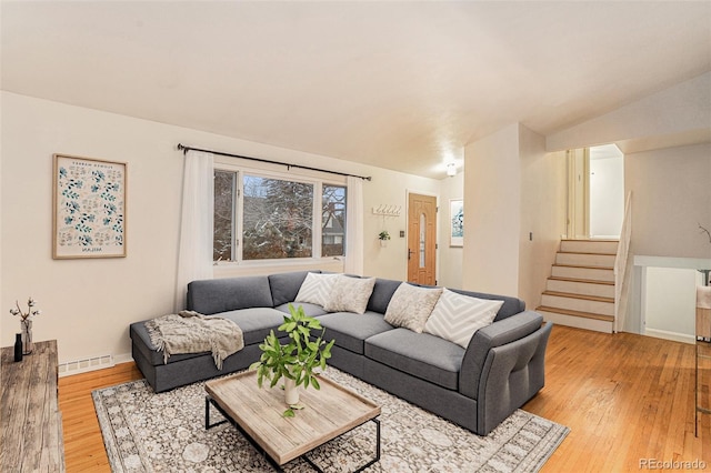 living area with light wood-style flooring, stairs, visible vents, and vaulted ceiling