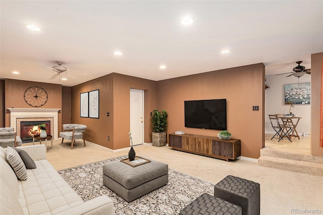 living room with recessed lighting, a warm lit fireplace, light carpet, and ceiling fan