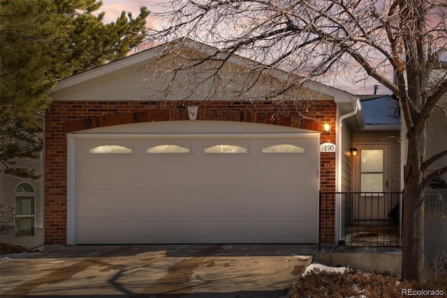 garage at dusk featuring driveway