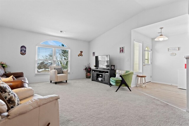 living room featuring visible vents, carpet, and vaulted ceiling