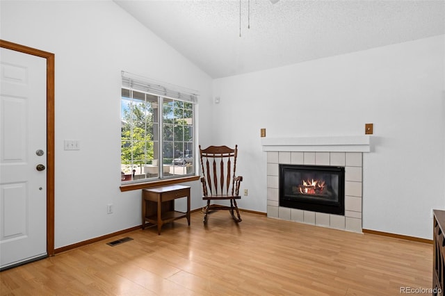 8761 Cloverleaf Cir, Parker, CO 80134 - sitting room with wood finished floors, lofted ceiling, a tile fireplace, and a textured ceiling