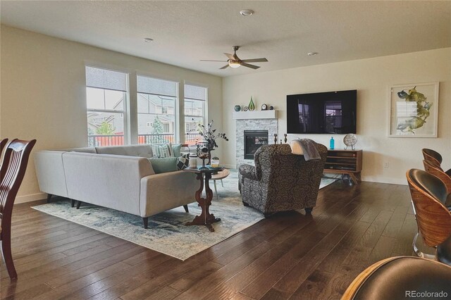 living room featuring hardwood / wood-style floors, ceiling fan, and a fireplace