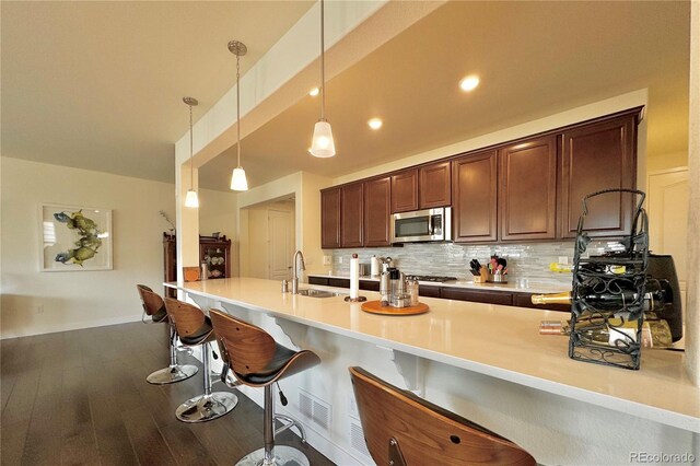 kitchen featuring decorative light fixtures, dark brown cabinetry, sink, tasteful backsplash, and hardwood / wood-style flooring