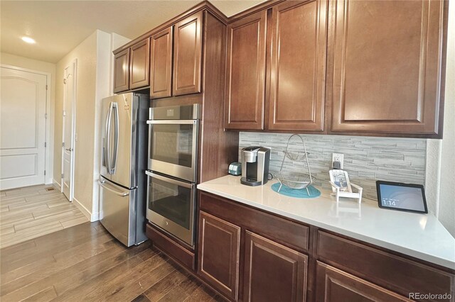 kitchen with hardwood / wood-style flooring, decorative backsplash, and appliances with stainless steel finishes