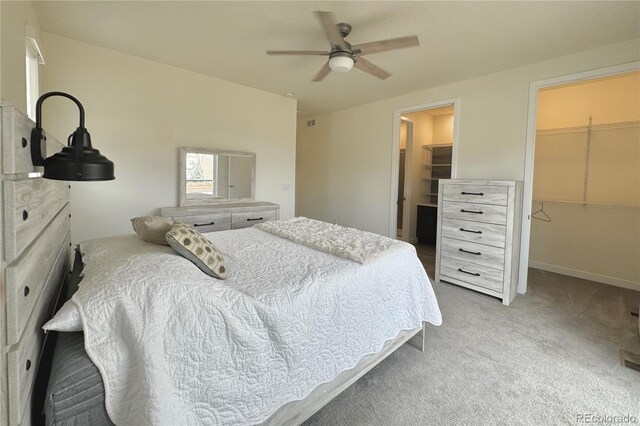 carpeted bedroom with a walk in closet, a closet, and ceiling fan