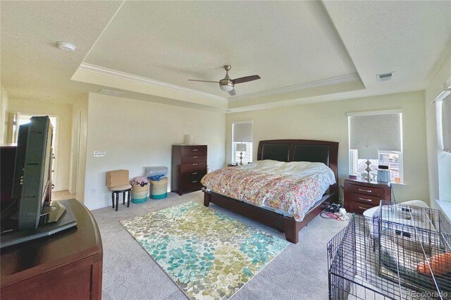 carpeted bedroom featuring ceiling fan and a raised ceiling