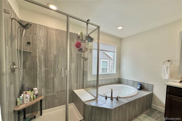 bathroom with separate shower and tub, a textured ceiling, and vanity