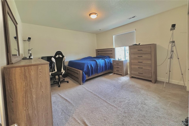 bedroom with a textured ceiling and light carpet