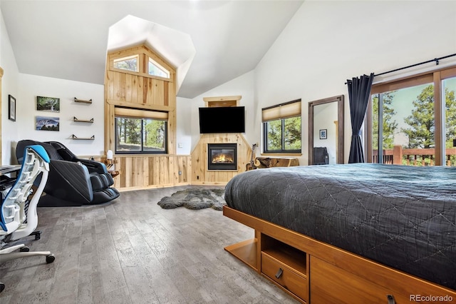 320 Summit Rd, Woodland Park, CO 80863 - bedroom featuring lofted ceiling, wood-type flooring, a fireplace, multiple windows, and a wainscoted wall