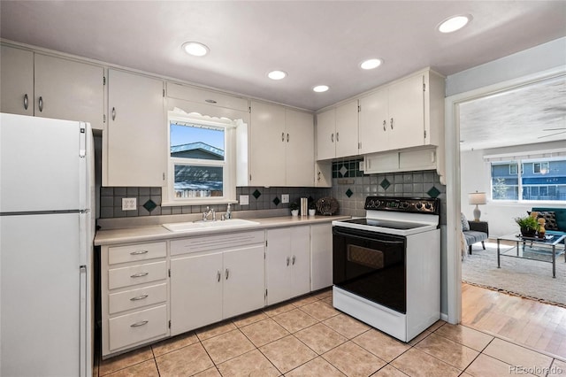 kitchen featuring white appliances, light hardwood / wood-style flooring, backsplash, sink, and white cabinets