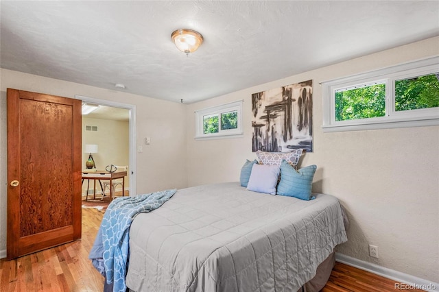 bedroom with wood-type flooring and multiple windows