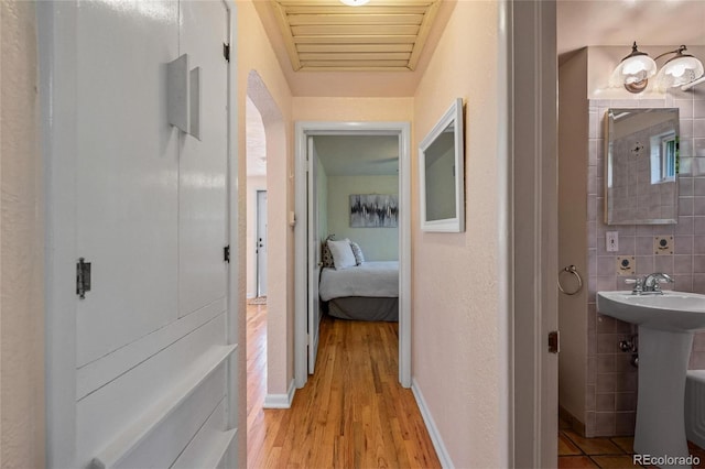 hall featuring tile walls, light hardwood / wood-style flooring, and sink